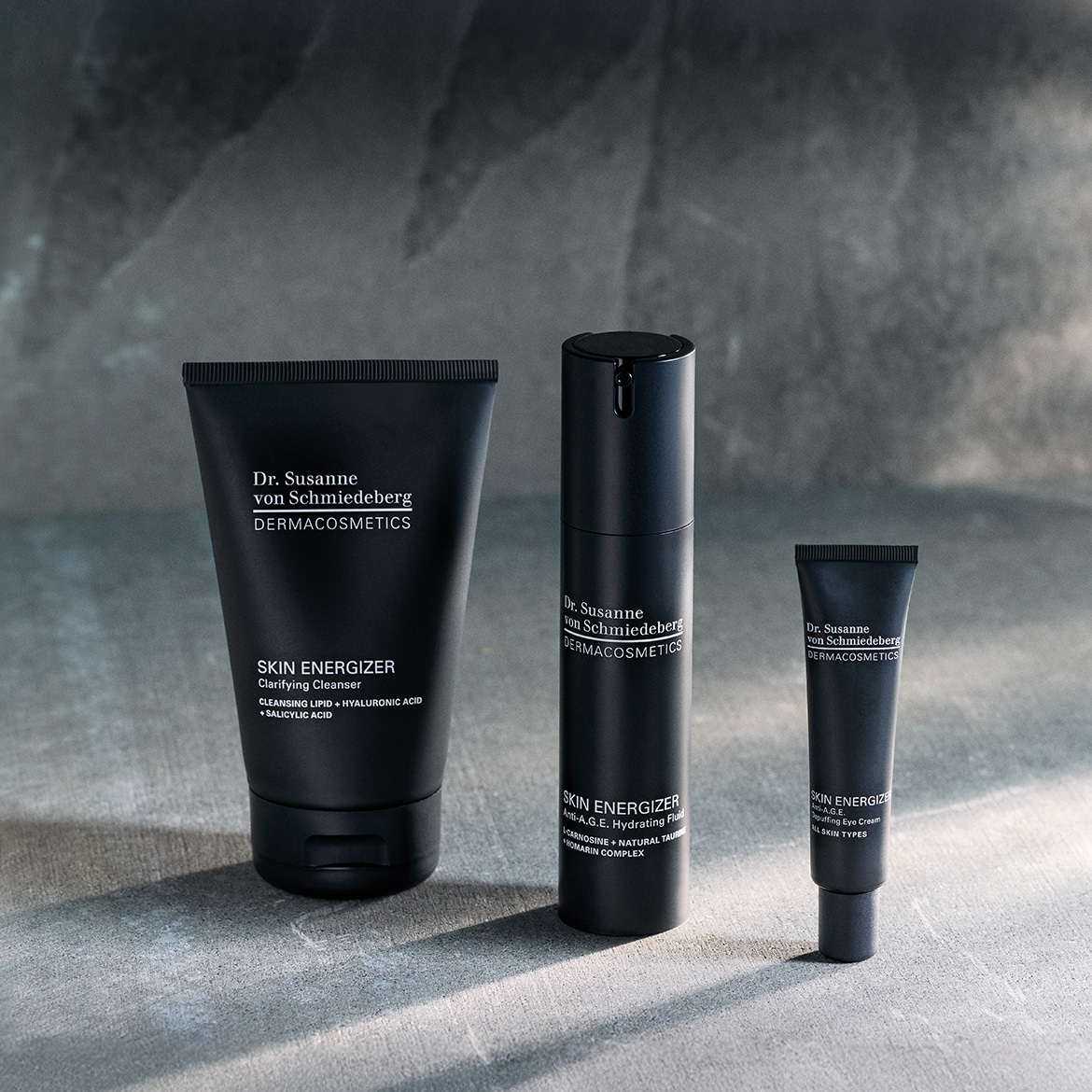 Découvrez le trio de soins Dr. Susanne von Schmiedeberg DERMACOSMETICS, comprenant un nettoyant clarifiant, un fluide hydratant anti-âge et une crème contour des yeux, le tout dans un élégant packaging noir.