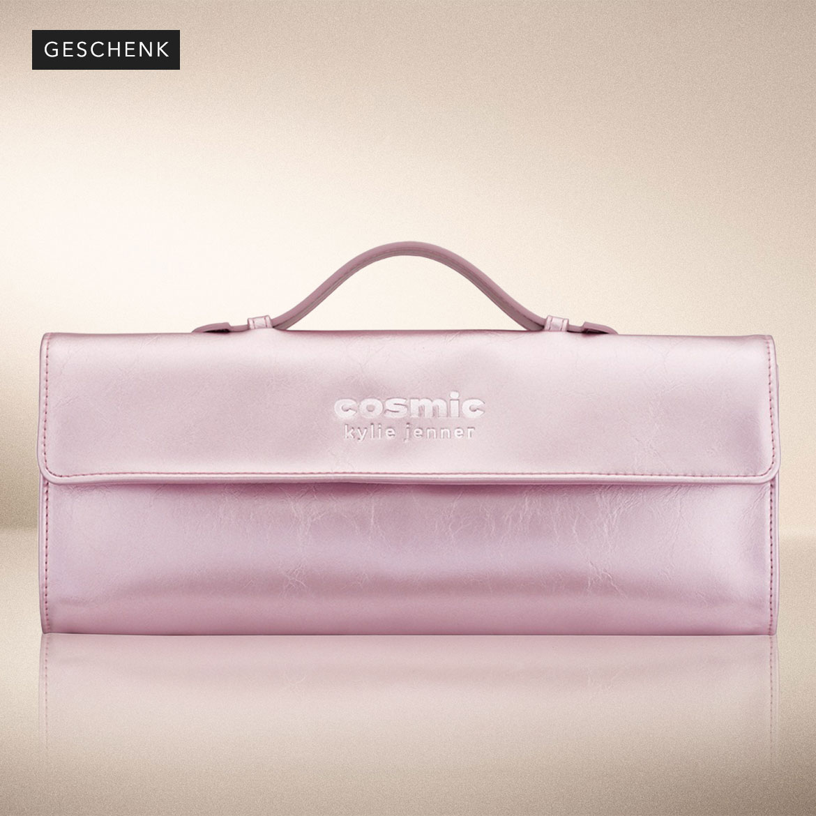 Nahaufnahme einer Kosmetiktasche in glänzendem Rosa mit dem Schriftzug 'cosmic kylie jenner' in Weiß, die als Geschenk angeboten wird.