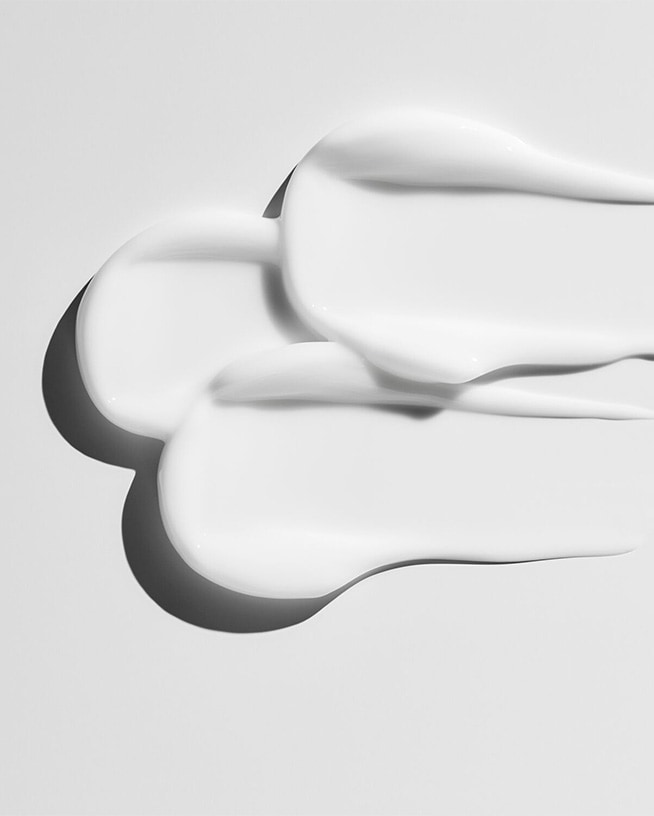 Nahaufnahme von weißen Sonnencreme-Texturen, die die reichhaltige und schützende Konsistenz für empfindliche Haut hervorheben.