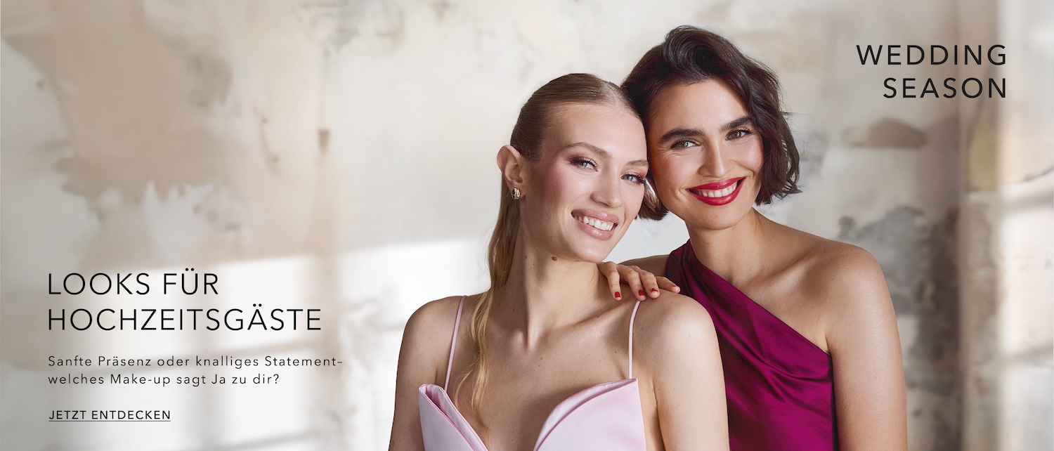 Zwei lächelnde Frauen – die eine in einem hellrosa Kleid, die andere in einem magentafarbenen Kleid – präsentieren Looks für Hochzeitsgäste und laden Sie ein, Ihren perfekten Make-up-Stil für diese Saison zu entdecken.